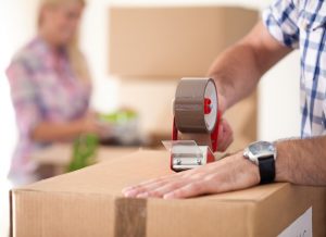 .Close up of male hand packing cardboard box, concept moving house